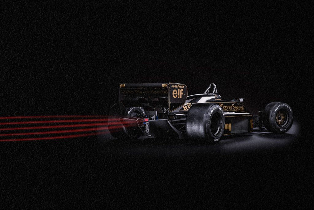 Carro de corrida de Senna correndo rapidamente em um cenário escuro. 