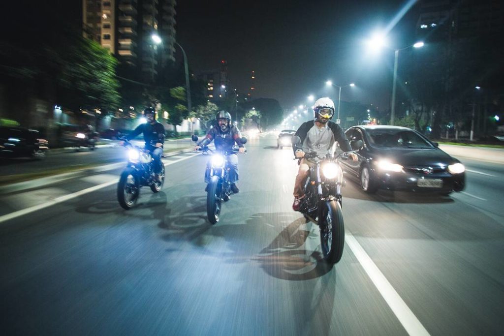 três motoqueiros andando de moto a noite